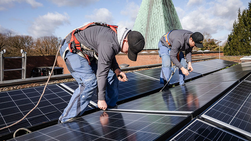 Zwei Arbeiter am Dach bei der Montage von Solarzellen